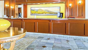 Een receptiezone met een houten paneelwand, een groot landschapsschilderij en een betegelde vloer.
