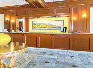 Uma área de recepção com painel de madeira, uma grande pintura de paisagem e piso de azulejos.