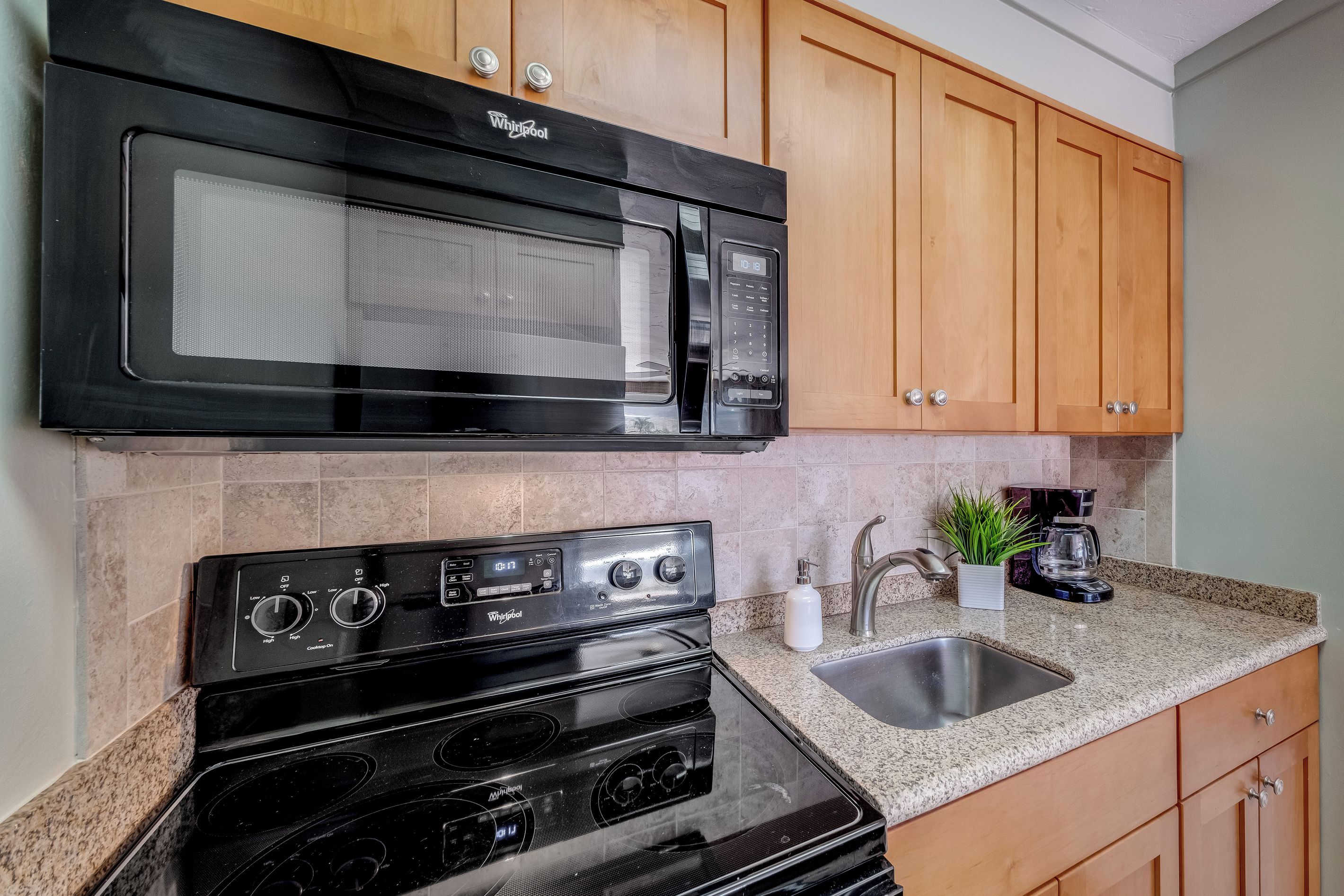 A kitchen with a black microwave, a stove, and wooden cabinets.