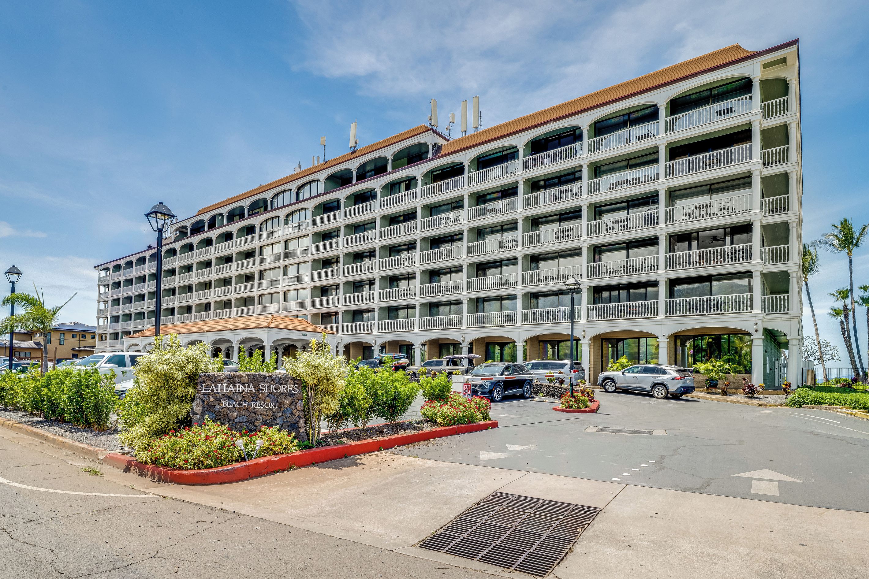 Un hôtel à plusieurs étages doté de balcons et d’un panneau indiquant un complexe hôtelier en bord de mer.
