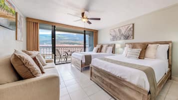 A hotel room with a balcony, a bed, a sofa, and a dining table.