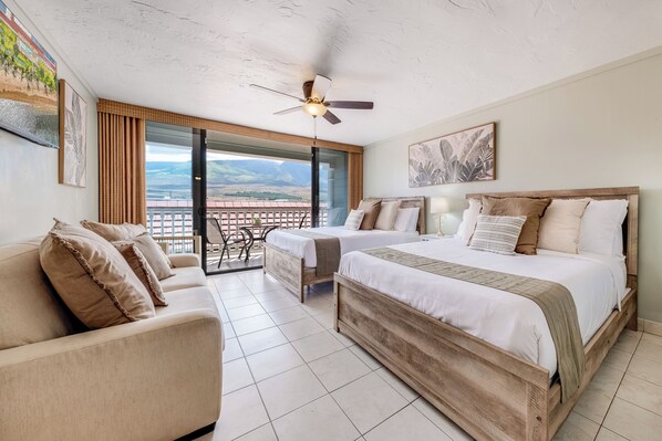 Une chambre d’hôtel avec un balcon, un lit, un canapé et une table à manger.