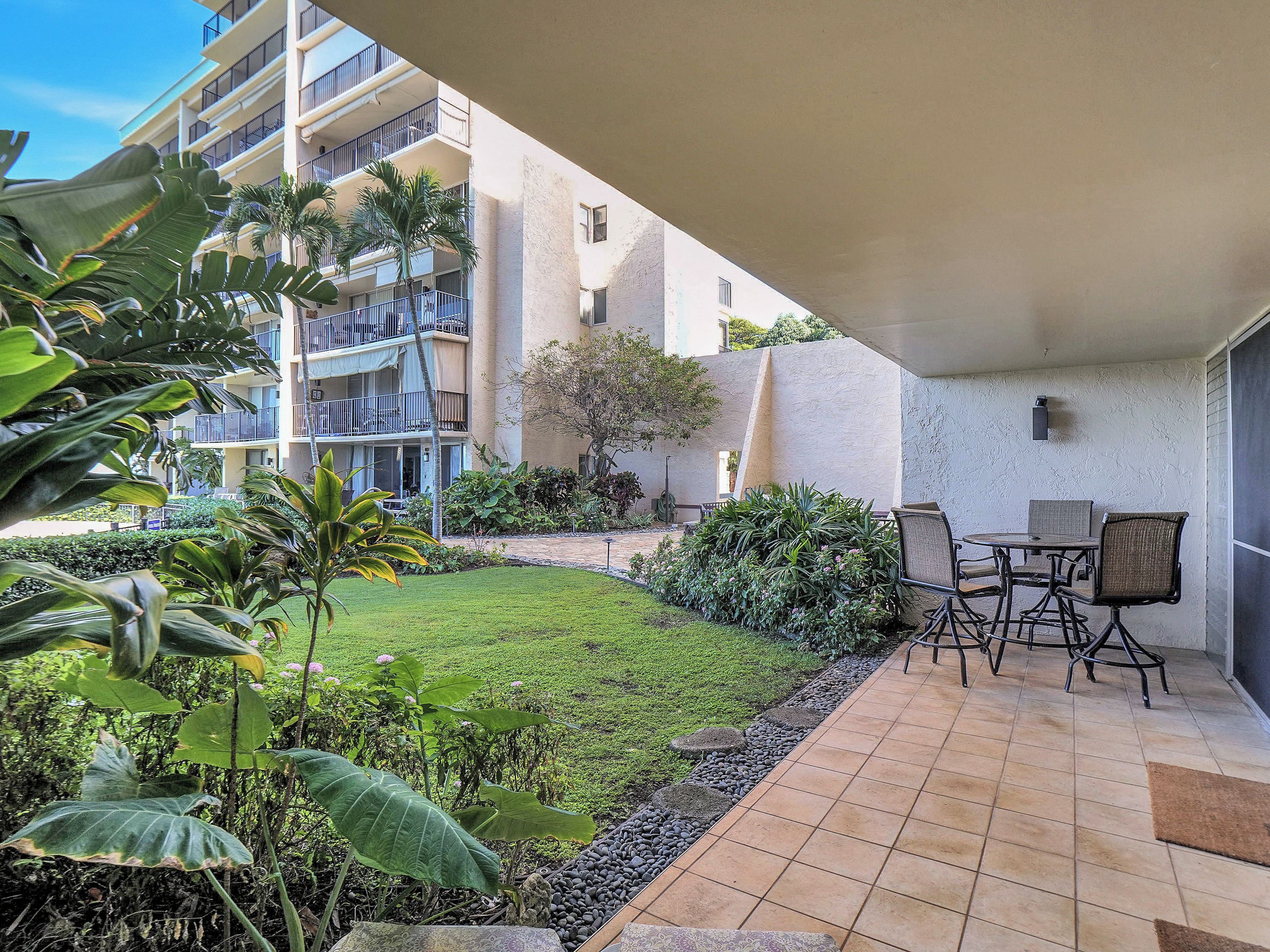 A hotel courtyard with a patio area, outdoor seating, and a view of the building's balconies.