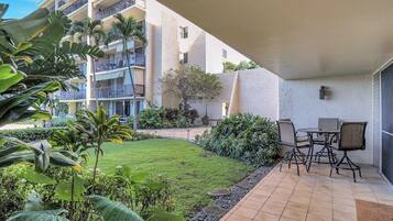 A hotel courtyard with a patio area, outdoor seating, and a view of the building's balconies.