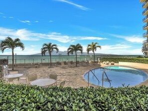 Zona junto a la piscina con sillones de descanso y una piscina pequeña, con vista a una playa y el océano.
