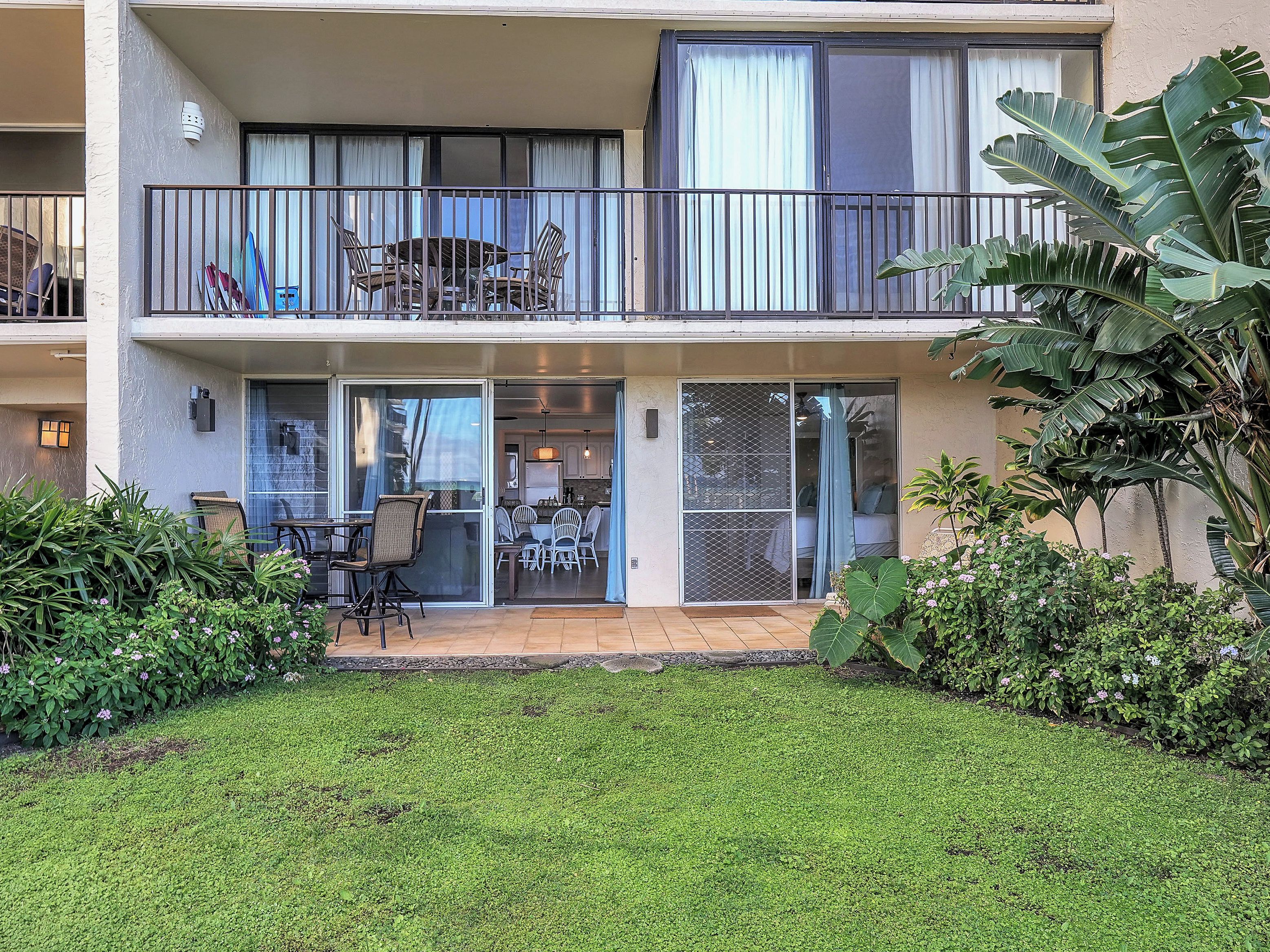 A two-story residential building with a balcony, sliding glass doors, and a small patio area.