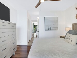 Ein Schlafzimmer mit einem Bett, einem Schminktisch, einem gerahmten Bild und einem Nachttisch.