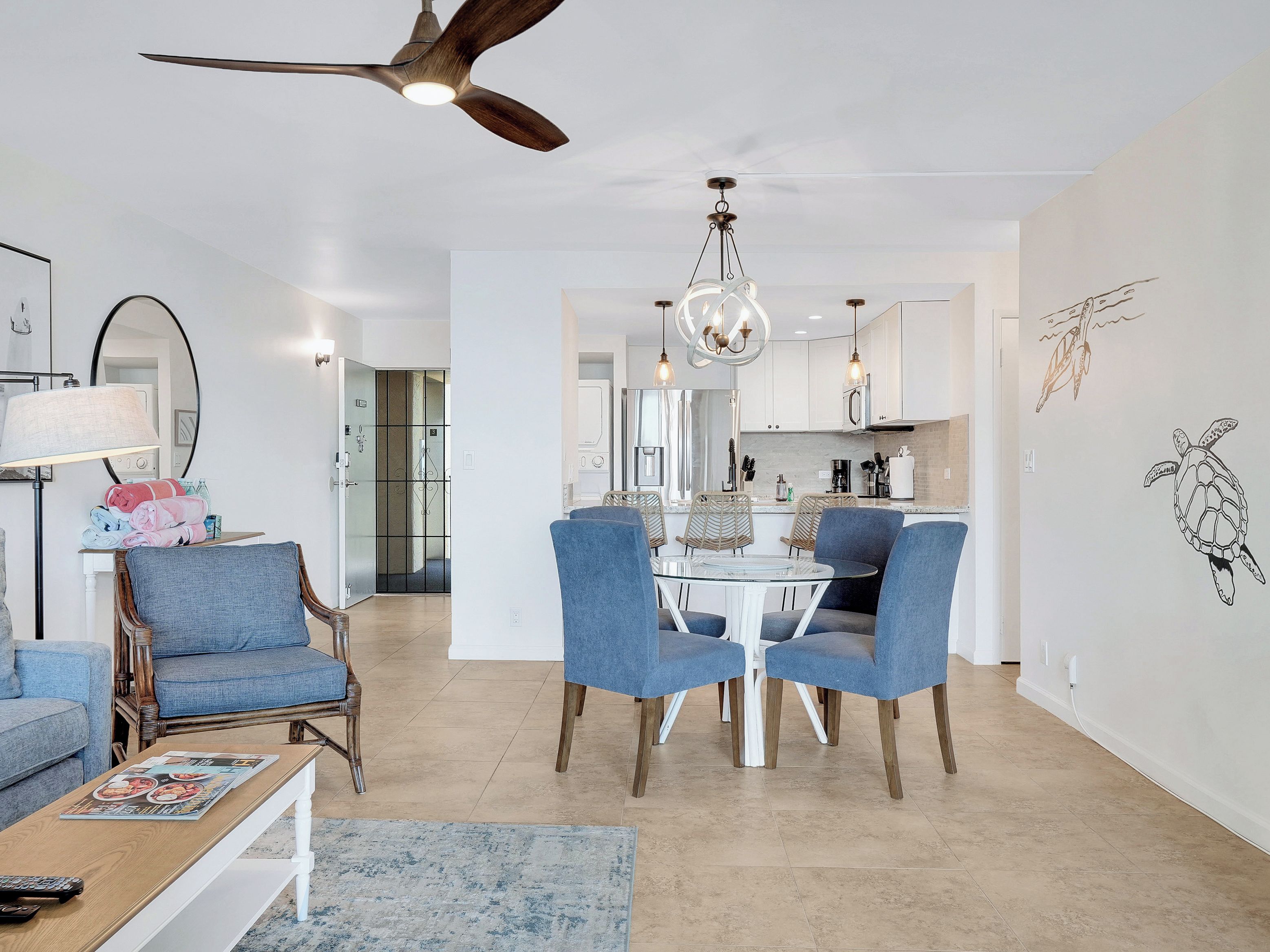 Un salon moderne avec un coin repas, un ventilateur de plafond et une cuisine en arrière-plan.