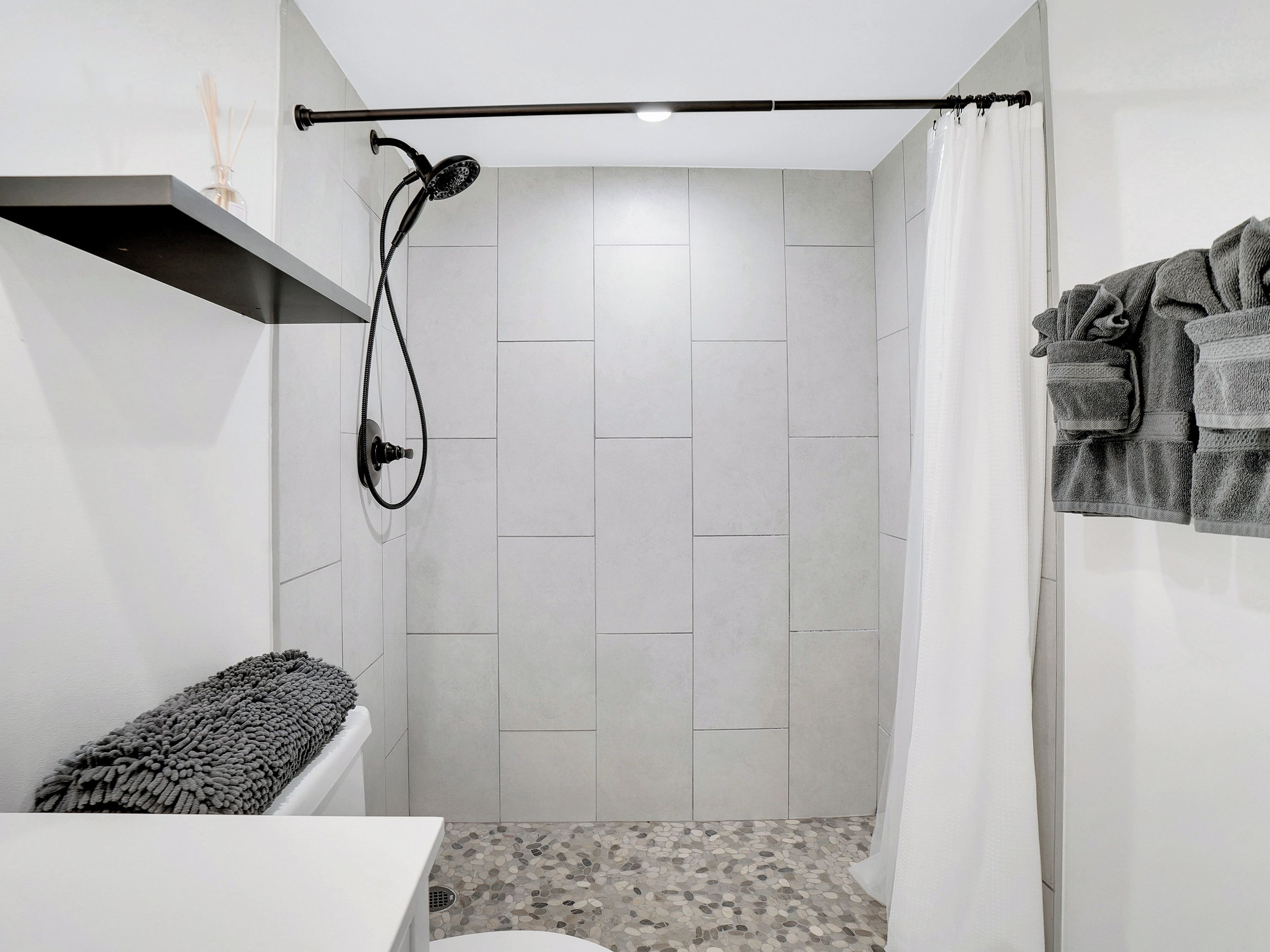 Een kleine, moderne badkamer met een douche, toilet en handdoekhouder.