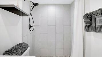 A small, modern bathroom with a shower, a toilet, and a towel rack.
