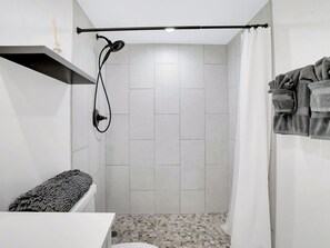 Ein kleines, modernes Badezimmer mit Dusche, Toilette und Handtuchhalter.
