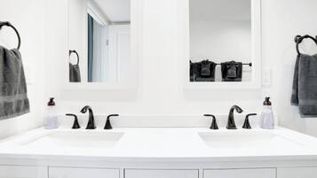 Une salle de bain moderne avec deux vasques, des robinets noirs et un miroir au-dessus de chaque vasque.