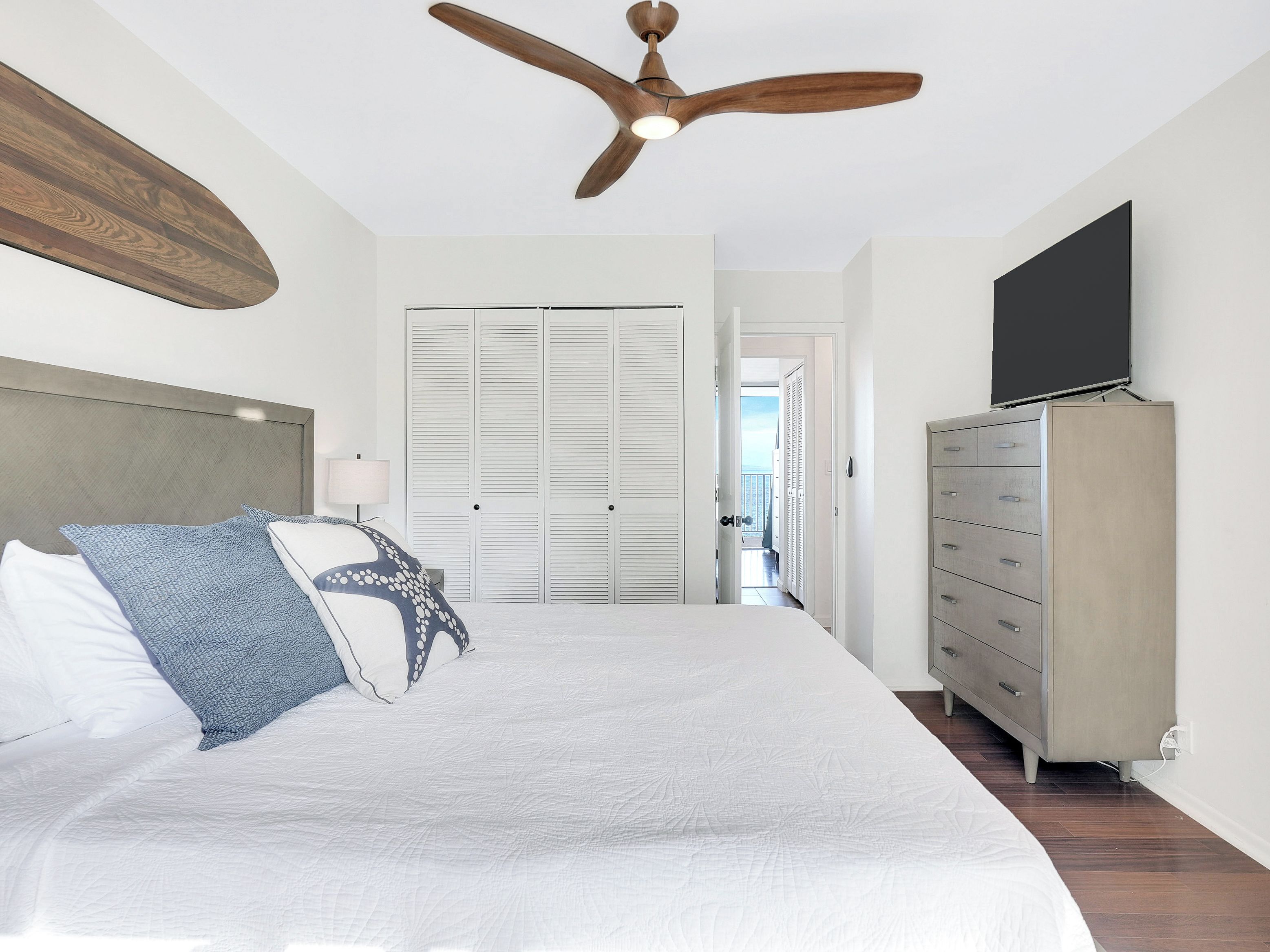 A bedroom with a bed, a ceiling fan, a wardrobe, and a television.
