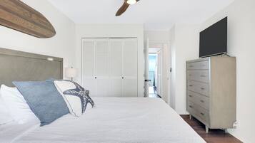 A bedroom with a bed, a ceiling fan, a wardrobe, and a television.