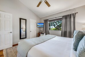 A bedroom with a bed, a television, a window with curtains, and a ceiling fan. - Relax in Kihei | Ocean View Condo, Pool, Hot Tub, Walk to Beach (Kihei)