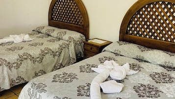A hotel room with two beds, each with a wooden headboard and a floral-patterned bedspread.