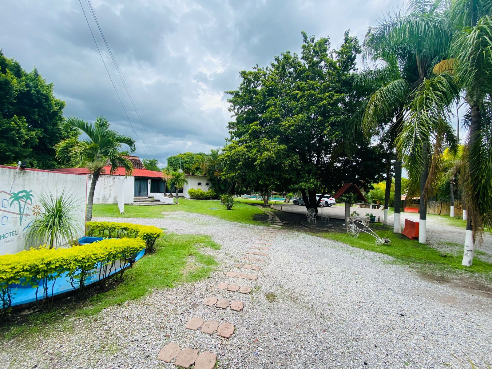 Un patio de hotel con un sendero de grava, césped verde y palmeras.
