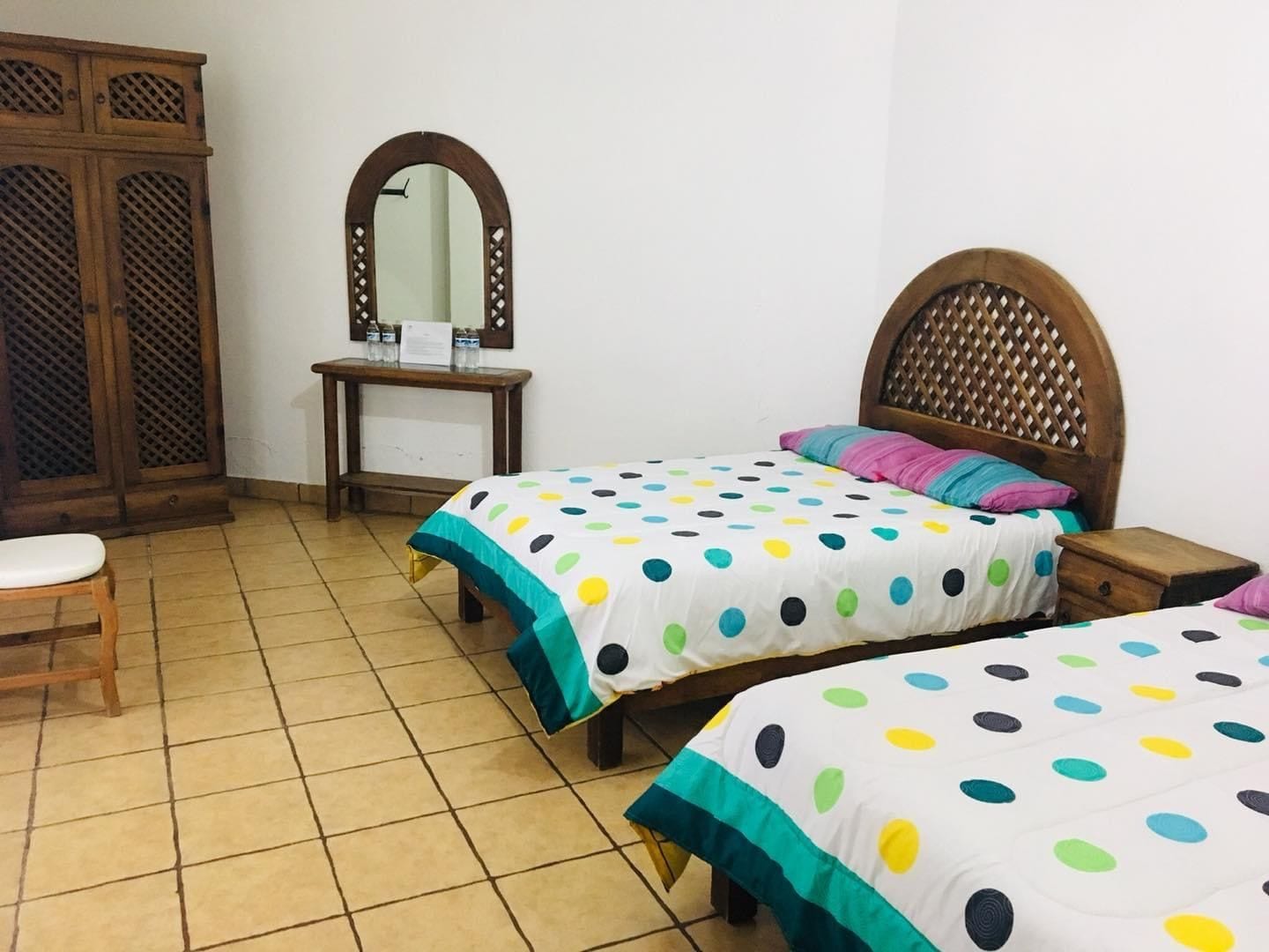 Un dormitorio con dos camas, un armario de madera, un escritorio con espejo y una silla.
