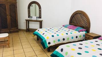 Un dormitorio con dos camas, un armario de madera, un escritorio con espejo y una silla.
