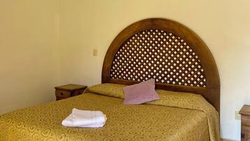 A hotel room with a bed, a nightstand, a wall-mounted air conditioner, and a ceiling light fixture.