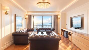 A spacious living room with a large sectional sofa, a coffee table, and a television mounted on the wall.