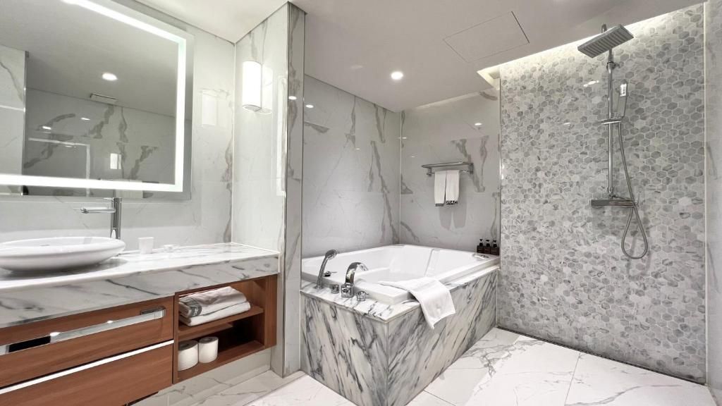 Un baño moderno con tocador de mármol, una bañera grande y una ducha con pared de piedra.