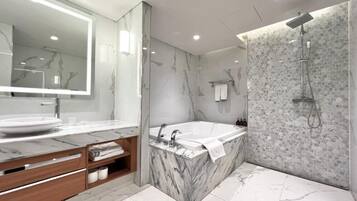 Un baño moderno con tocador de mármol, una bañera grande y una ducha con pared de piedra.