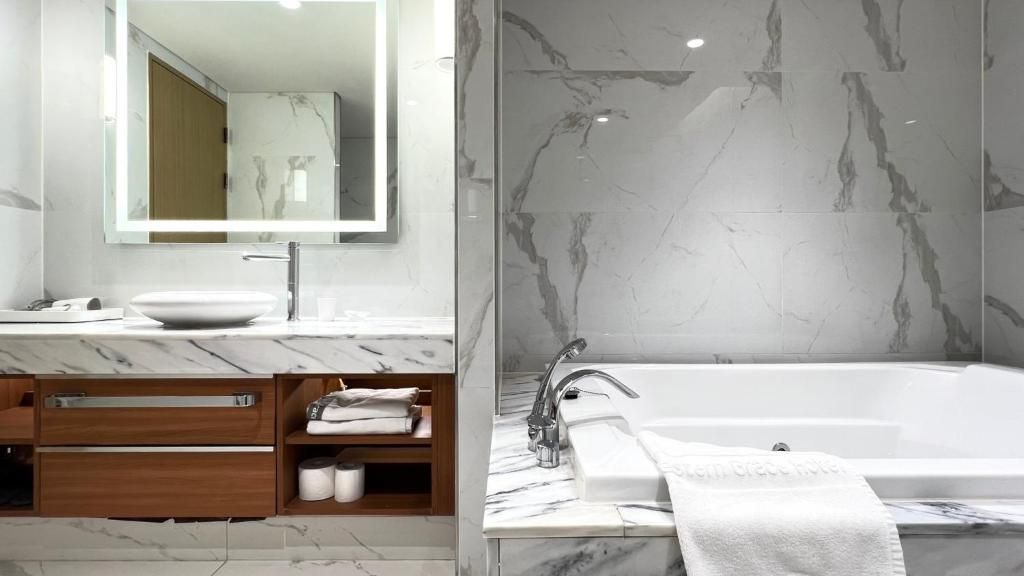 Un baño moderno con lavamanos de mármol, un espejo grande, tocador de madera y una bañera.