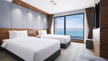 Habitación de hotel con dos camas, un ventanal con vistas y un televisor de pantalla plana.