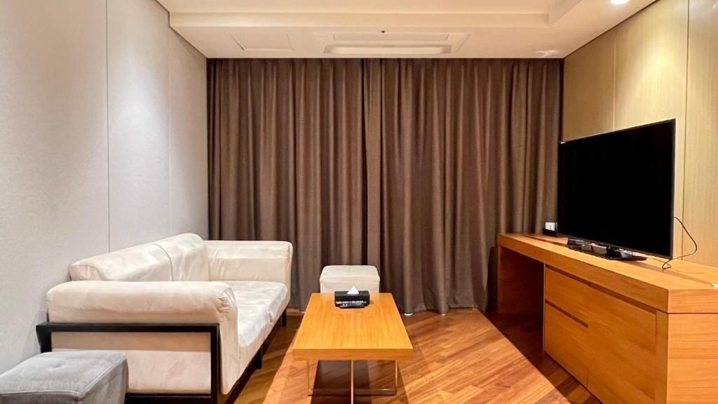 A hotel room with a sofa, a small table, a TV, and a wooden cabinet.