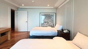 Quarto com cama, mesas de cabeceira, escrivaninha e porta.