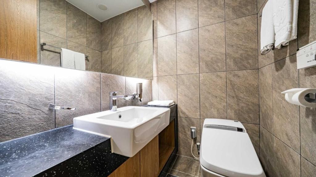 A modern bathroom with a sink, mirror, and toilet.