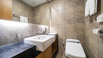 A modern bathroom with a sink, mirror, and toilet.