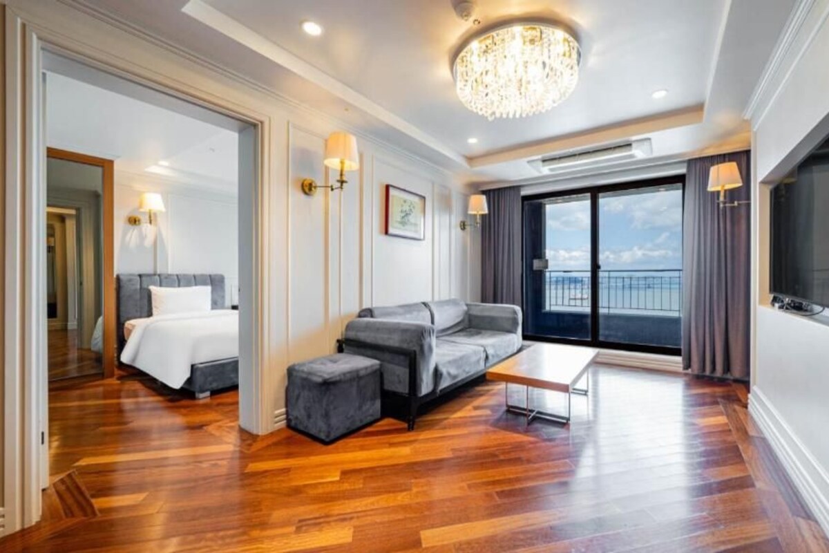 Quarto de hotel moderno com cama, sofá e varanda com vista.