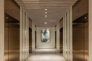 A corridor with a modern design, featuring a central artwork and glass elevator doors. - Queen's Wharf Residences Luxury 2 Beds 1 Car (Brisbane)
