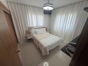 Una habitación de hotel con una cama, mesita de noche y una lámpara del techo.
