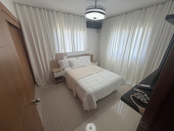 A hotel room with a bed, nightstand, and a ceiling light fixture.