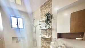 Un bagno moderno dotato di doccia, toilette, lavandino e specchio sopra il lavandino.