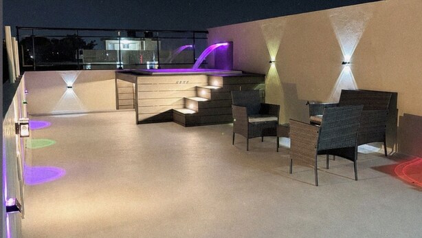 Una terrazza esterna con zona bar, posti a sedere e illuminazione soffusa.