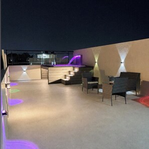 An outdoor terrace with a bar area, seating, and ambient lighting.
