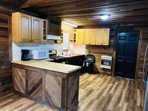 A kitchen with wooden cabinets, a central island, a microwave, a coffee maker, and a built-in oven.