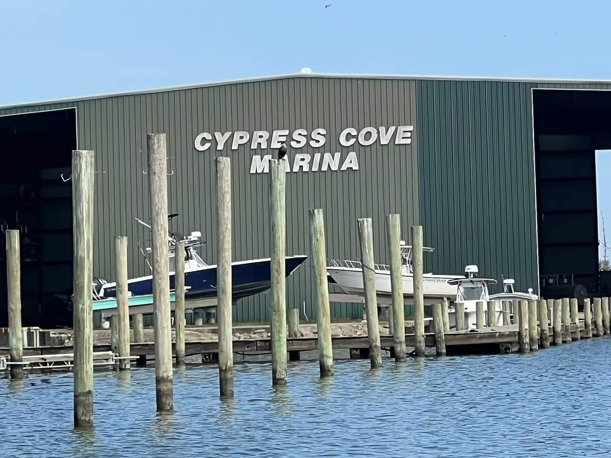 Un port de plaisance où des bateaux sont amarrés devant un bâtiment portant l’inscription « CYPRESS COVE MARINA ».