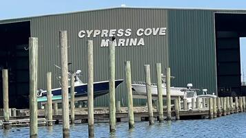 Un port de plaisance où des bateaux sont amarrés devant un bâtiment portant l’inscription « CYPRESS COVE MARINA ».