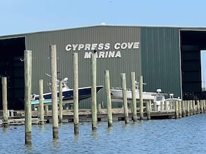 Un port de plaisance où des bateaux sont amarrés devant un bâtiment portant l’inscription « CYPRESS COVE MARINA ».