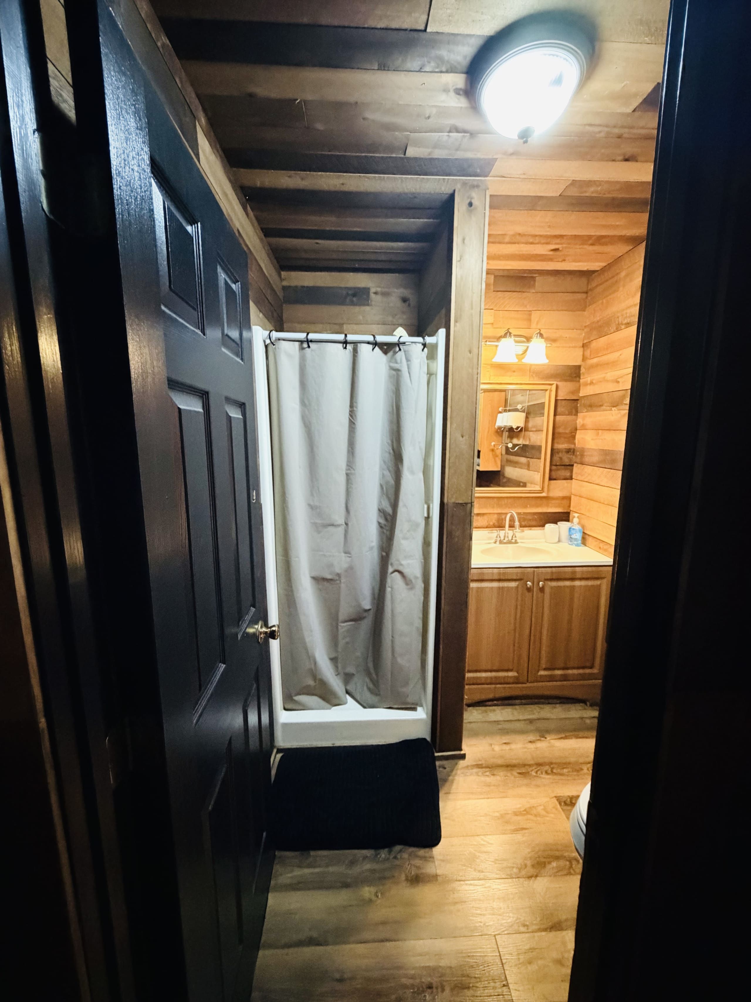 Ein Holzinnenraum mit Dusche, Waschbecken und Spiegel.