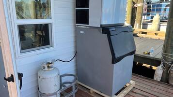 A compact room with a window, a large gray refrigerator, and a white propane tank.