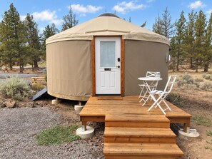 A yurt with a wooden deck and a table with chairs outside. - Lumberjack 20' Yurt, King Bed Glamping in Bend (Bend)