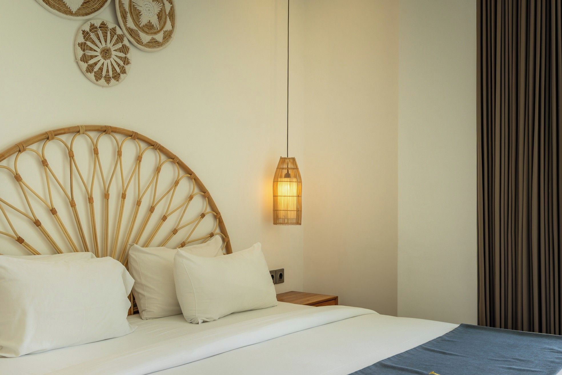 A bed with a circular headboard, a bedside lamp, and a wall with decorative plates.