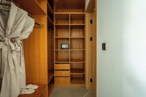 Un vestidor con estantes y cajones de madera, una barra para colgar ropa y una caja fuerte pequeña.