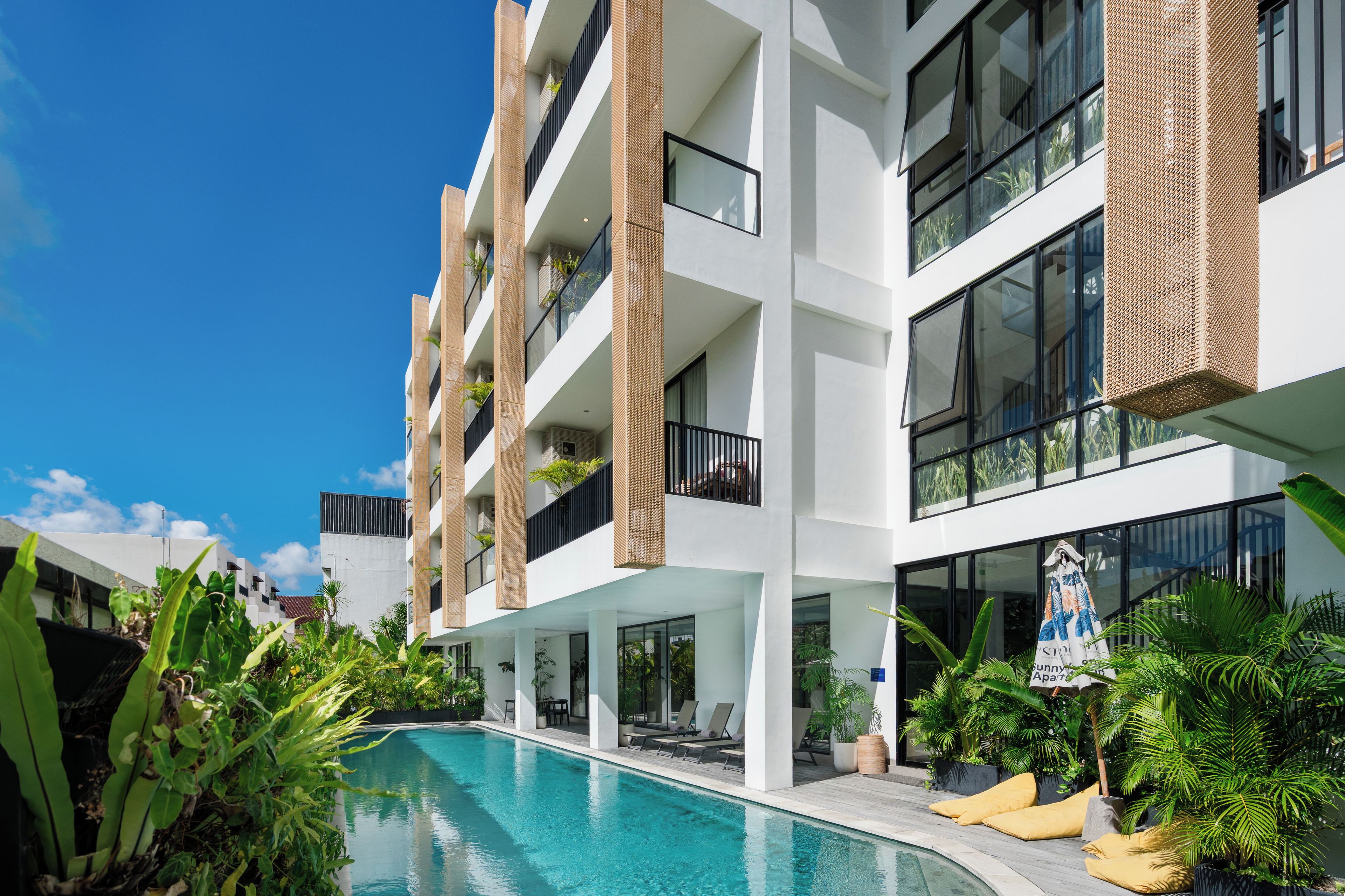 A multi-story hotel with a swimming pool, outdoor seating, and balconies.
